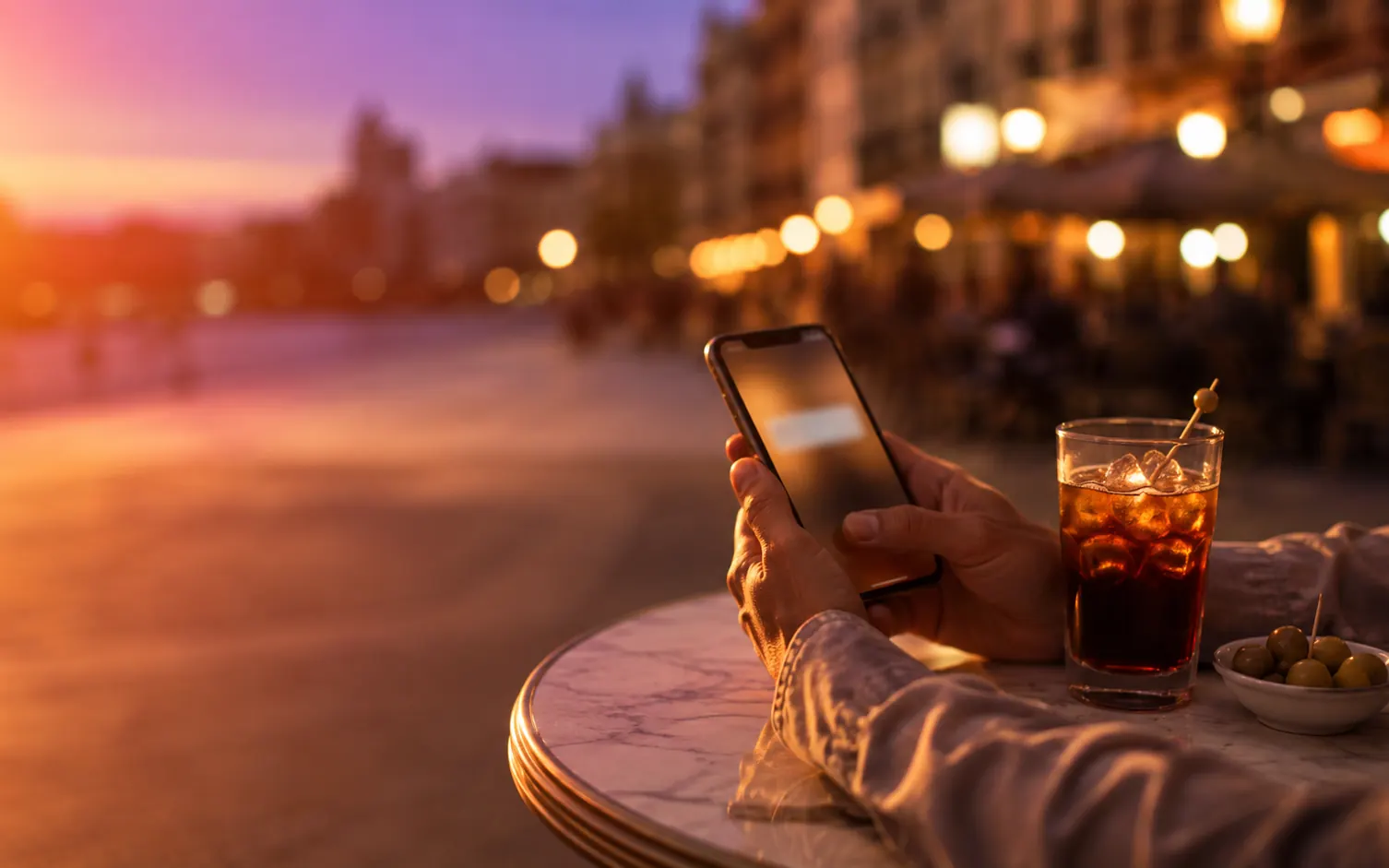 A guest having a drink nearby while waiting for the table alert on their phone